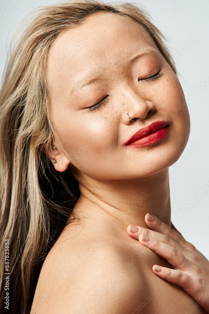 Fototapeta premium Asian woman in vibrant clothing, eyes closed, hands on chest