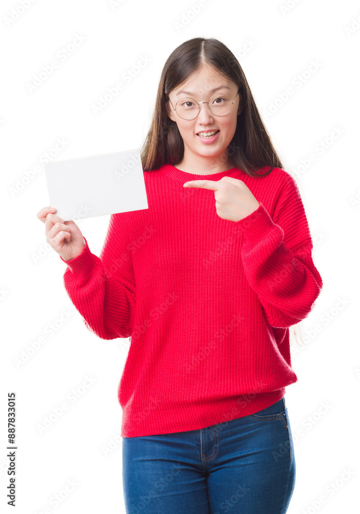 Young Chinese woman over isolated background holding blank card very happy pointing with hand and finger Young Chinese woman over isolated background holding blank card very happy pointing with hand and finger