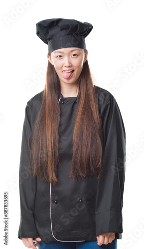 Young Chinese woman over isolated background wearing chef uniform sticking tongue out happy with funny expression. Emotion concept.