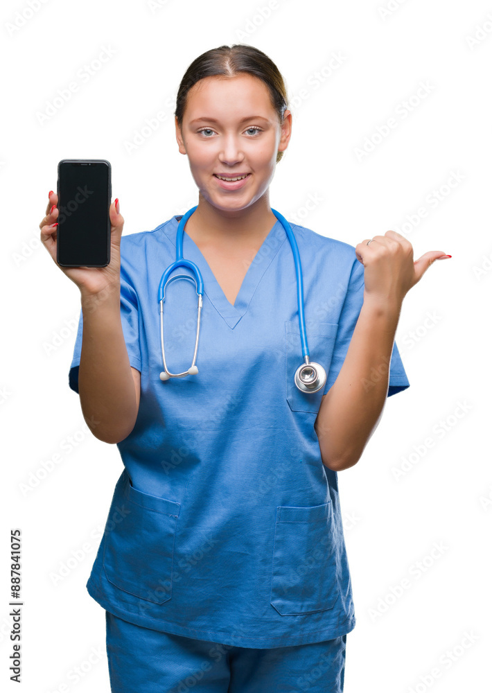 Young caucasian doctor woman showing smarpthone over isolated background pointing and showing with thumb up to the side with happy face smiling Young caucasian doctor woman showing smarpthone over isolated background pointing and showing with thumb up to the side with happy face smiling