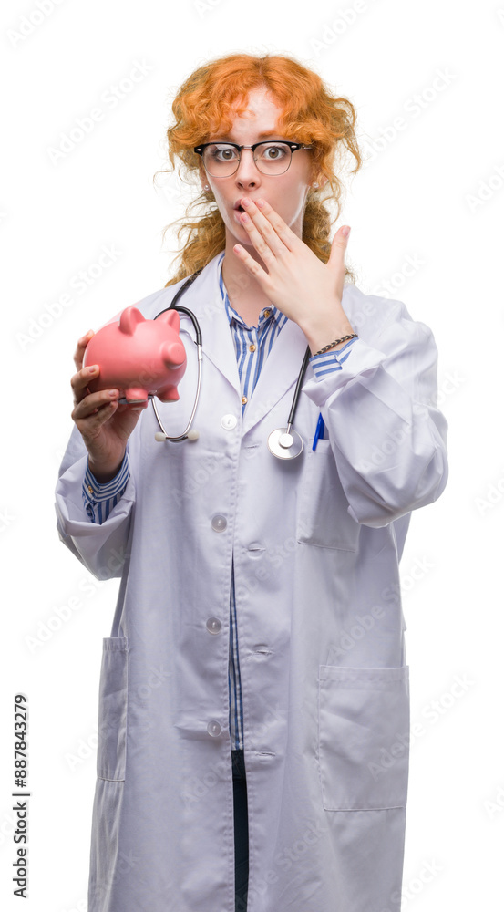 Young redhead doctor woman holding piggy bank cover mouth with hand shocked with shame for mistake, expression of fear, scared in silence, secret concept Young redhead doctor woman holding piggy bank cover mouth with hand shocked with shame for mistake, expression of fear, scared in silence, secret concept