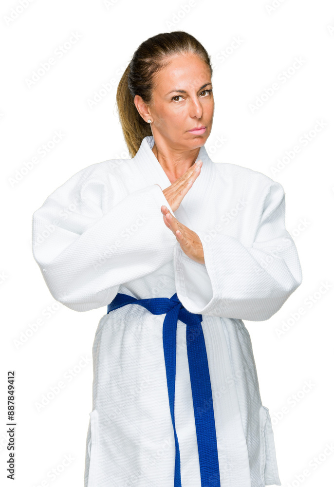 Middle age adult woman wearing karate kimono uniform over isolated background with serious expression on face. Simple and natural looking at the camera. Middle age adult woman wearing karate kimono uniform over isolated background with serious expression on face. Simple and natural looking at the camera.