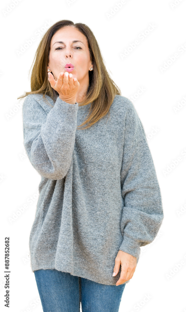 Beautiful middle age woman wearing winter sweater over isolated background looking at the camera blowing a kiss with hand on air being lovely and sexy. Love expression. Beautiful middle age woman wearing winter sweater over isolated background looking at the camera blowing a kiss with hand on air being lovely and sexy. Love expression.