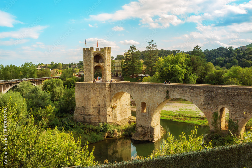 Obraz premium Besalu, Girona, Catalonia, Spain. Famous landmark. Old medieval Romanesque bridge Besalu over the river Fluvia on a sunny summer day.