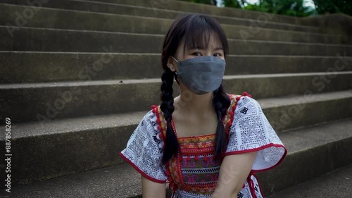 Woman in tribal costume wearing a mask Sitting on the steps smiling at the camera. photo