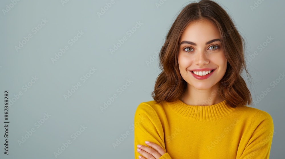 A woman in a yellow sweater is smiling and looking at the camera. She has her arms crossed and she is confident and happy A woman in a yellow sweater is smiling and looking at the camera. She has her arms crossed and she is confident and happy