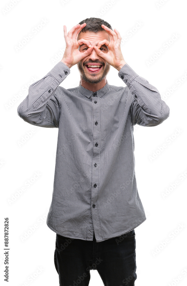 Young hipster man doing ok gesture like binoculars sticking tongue out, eyes looking through fingers. Crazy expression. Young hipster man doing ok gesture like binoculars sticking tongue out, eyes looking through fingers. Crazy expression.