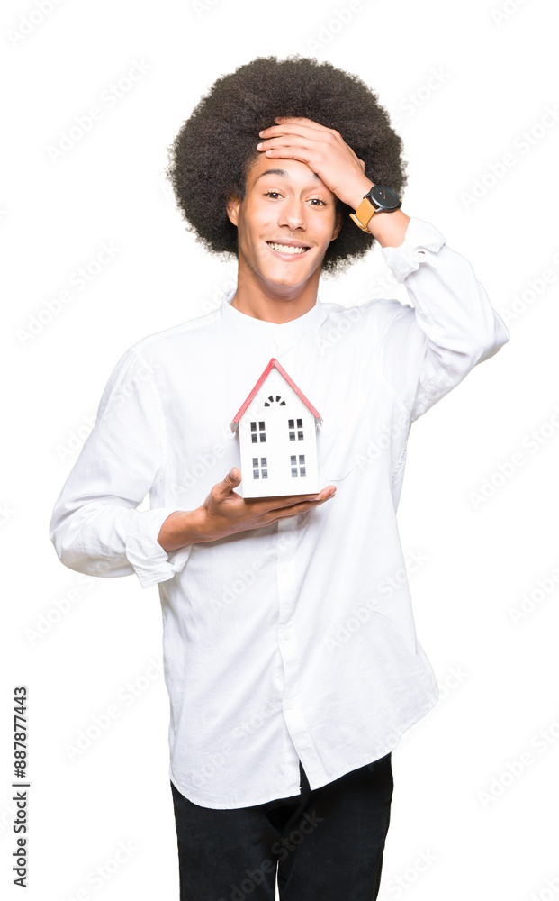 Young african american man with afro hair holding house stressed with hand on head, shocked with shame and surprise face, angry and frustrated. Fear and upset for mistake. Young african american man with afro hair holding house stressed with hand on head, shocked with shame and surprise face, angry and frustrated. Fear and upset for mistake.