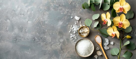 Spa ambiance featuring a gray background adorned with a yellow orchid green eucalyptus a cream bowl with spoon salt in a bowl and a designated area available for text. with copy space image