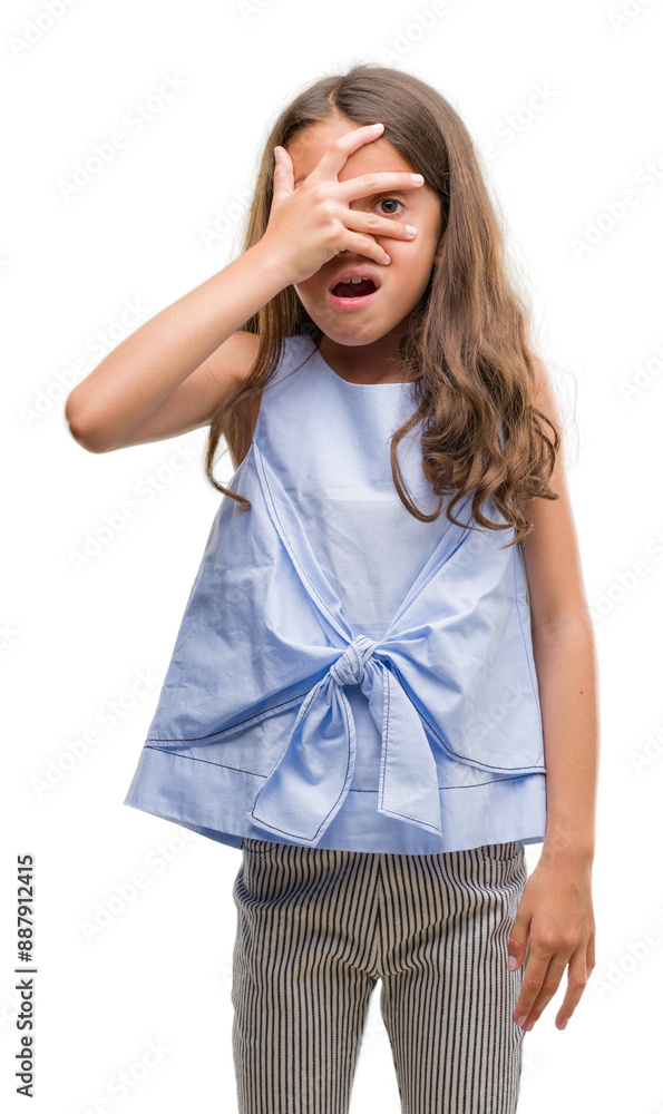 Brunette hispanic girl peeking in shock covering face and eyes with hand, looking through fingers with embarrassed expression. Brunette hispanic girl peeking in shock covering face and eyes with hand, looking through fingers with embarrassed expression.