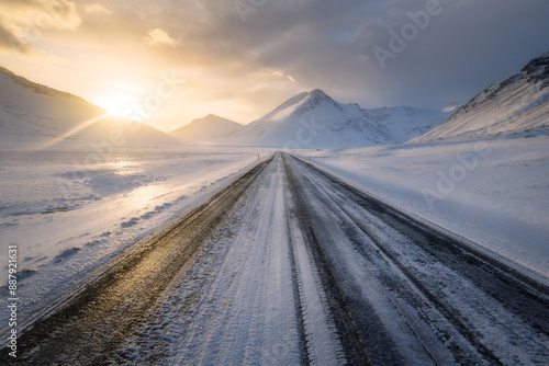 Obraz na płótnie Straight road in southern Iceland at sunset, in winter, icy slippery road with m
