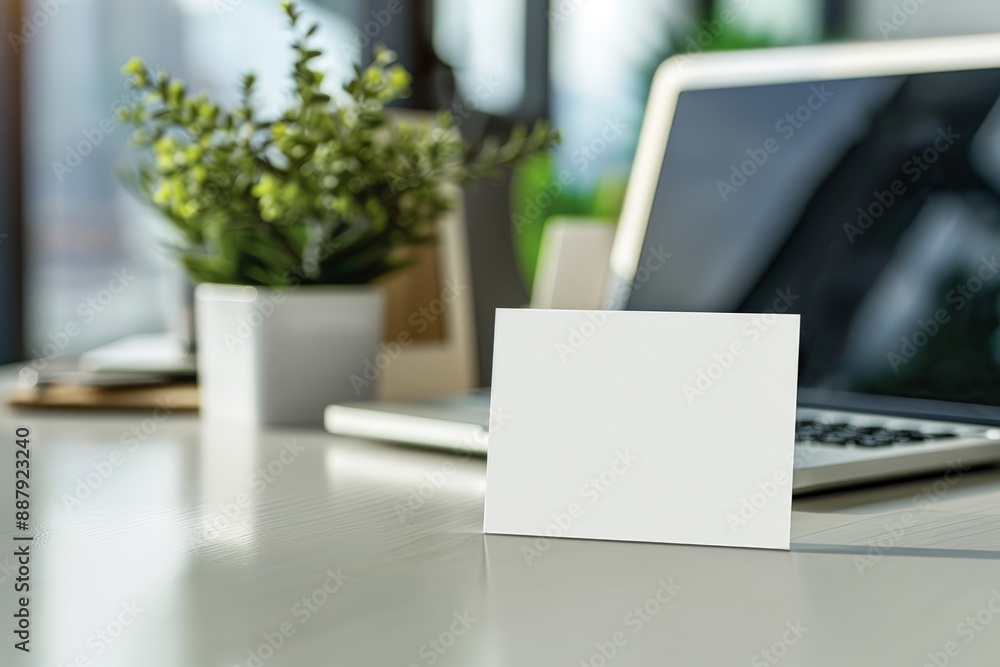 Blank business card on a sleek office desk with a laptop and plant Blank business card on a sleek office desk with a laptop and plant