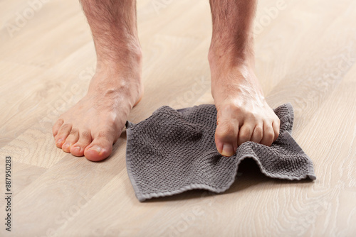 man doing flatfoot correction gymnastic exercise grabbing towel at home