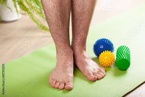 Obraz na płótnie man doing flatfoot correction gymnastic exercise using massage roller at home w salonie