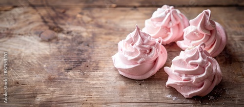 Delicate pink meringue on a rustic wooden surface with copy space image © Ilgun