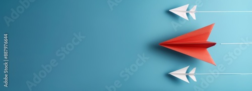 A red paper plane leads a group of white planes on a blue background banner with copy space area