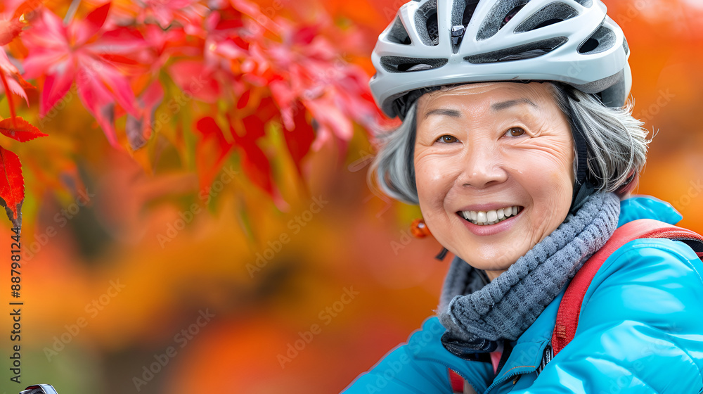 Elderly Asian gray hair woman in helmet and blue jacket biking through a park in autumn, enjoying the cool breeze and colorful leaves. Active and healthy senior lifestyle. Copy space. Elderly Asian gray hair woman in helmet and blue jacket biking through a park in autumn, enjoying the cool breeze and colorful leaves. Active and healthy senior lifestyle. Copy space.