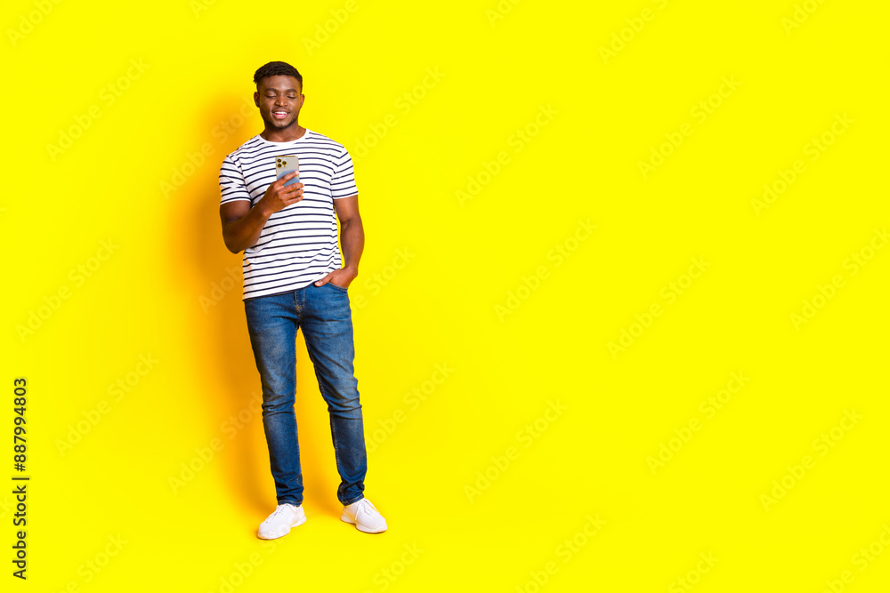 Full size photo of nice young man use phone empty space wear t-shirt isolated on bright yellow color background