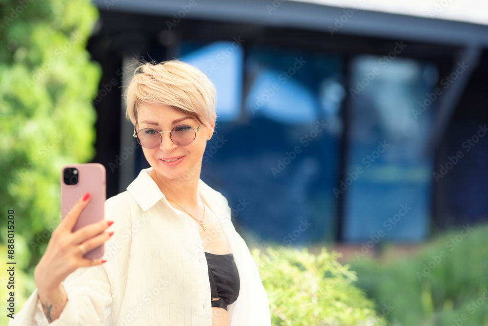 The girl holds the phone in her outstretched hand and smiles at the camera. Video conversation on the phone. Takes a selfie. Blogger The girl holds the phone in her outstretched hand and smiles at the camera. Video conversation on the phone. Takes a selfie. Blogger