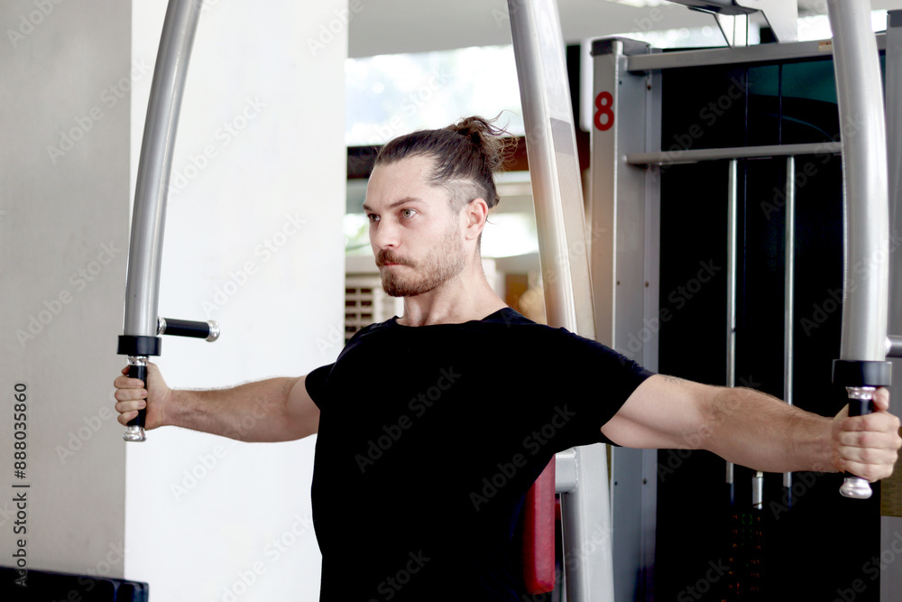 Fototapeta premium Strong muscular man exercising with sport equipment at gym. Sport man using chest press machine for exercise at fitness. Athletic workout training bodybuilding program for healthy and perfect body.