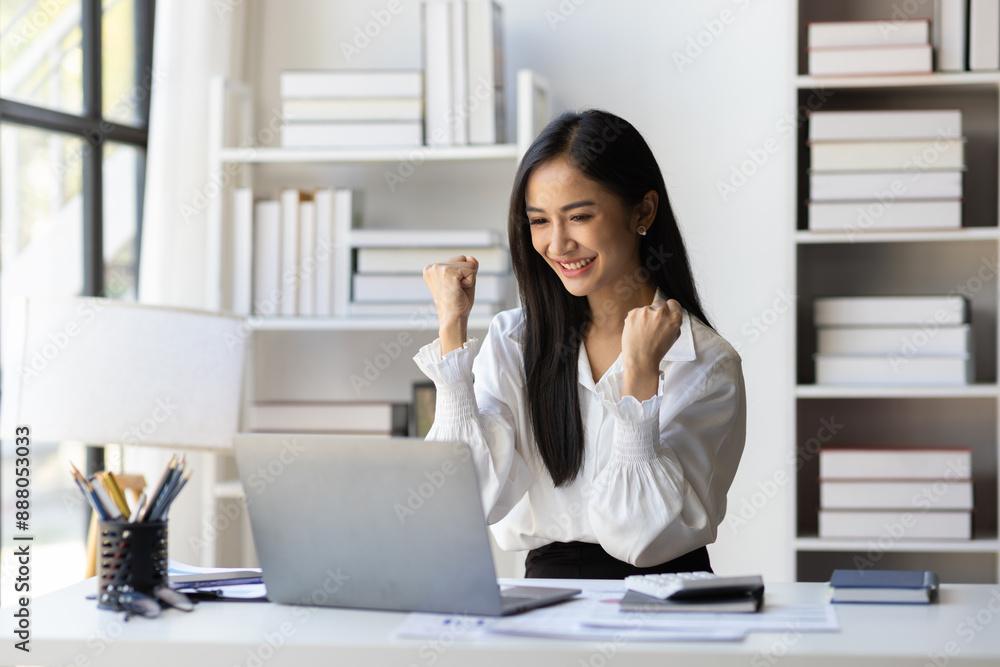 Successful Asian businesswoman happy looking at laptop and excited. Woman in office looking at laptop surprised to receive bonus and promotion. Successful Asian businesswoman happy looking at laptop and excited. Woman in office looking at laptop surprised to receive bonus and promotion.