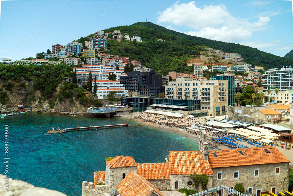 Obraz premium Budva, Montenegro. View of the bay, mountains, sea, modern hotel buildings and orange roofs of the old town