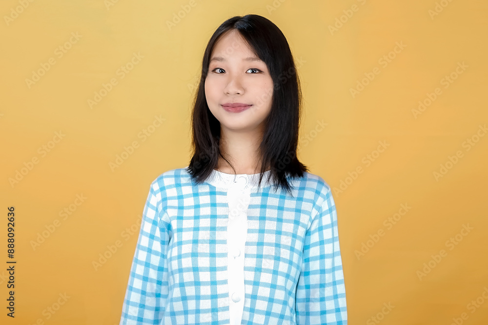 Portrait of a confident smiling girl standing with arms folded and looking at the camera isolated over yellow background Portrait of a confident smiling girl standing with arms folded and looking at the camera isolated over yellow background