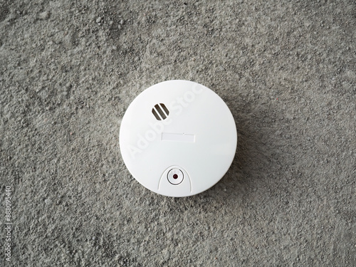 White smoke detector lying on gray concrete . Electronic device, asphalt, button .Fire safety .