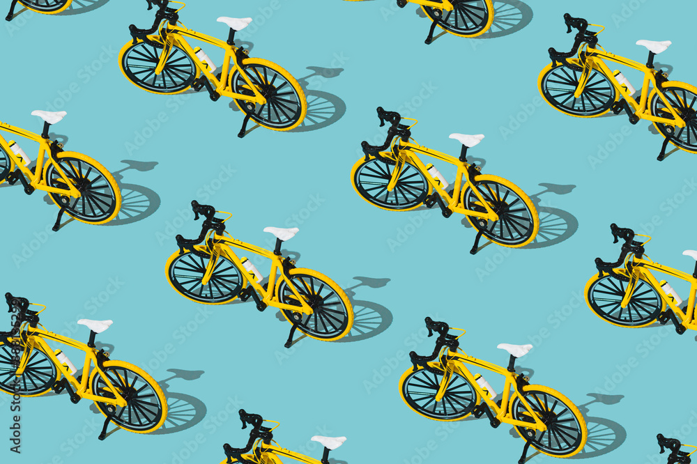 Fototapeta premium Trendy sport pattern made of yellow bicycle on pastel blue background. Minimal bicycling concept. Creative sport bike pattern backdrop idea.