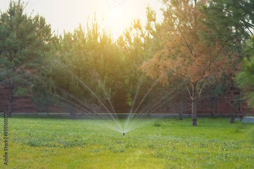 Automatic lawn watering system. Sprinkler, Water spashes on green grass. photo