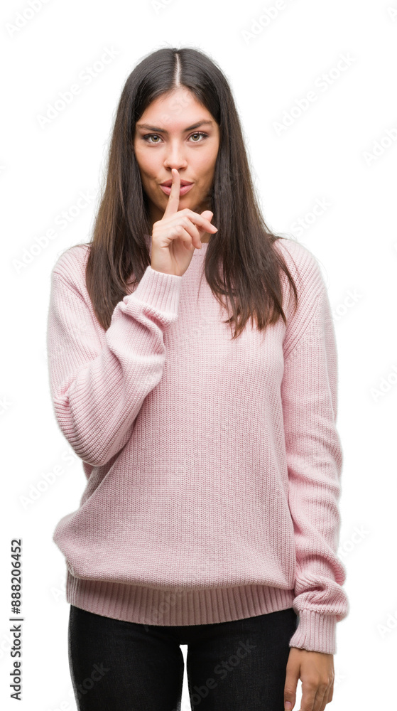 Young beautiful hispanic woman wearing a sweater asking to be quiet with finger on lips. Silence and secret concept.