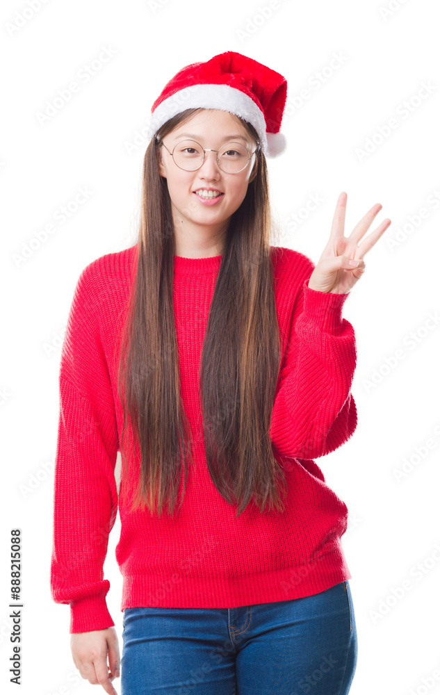 Young Chinese woman over isolated background wearing christmas hat showing and pointing up with fingers number three while smiling confident and happy. Young Chinese woman over isolated background wearing christmas hat showing and pointing up with fingers number three while smiling confident and happy.