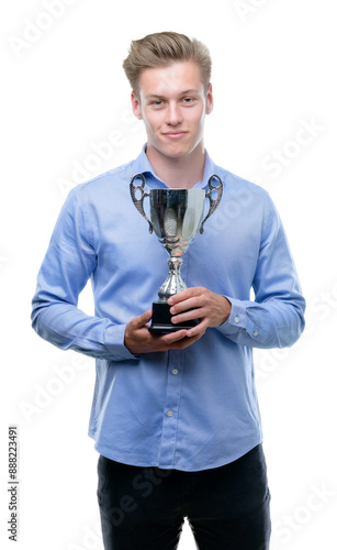 Young handsome blond man holding a trophy with a confident expression on smart face thinking serious