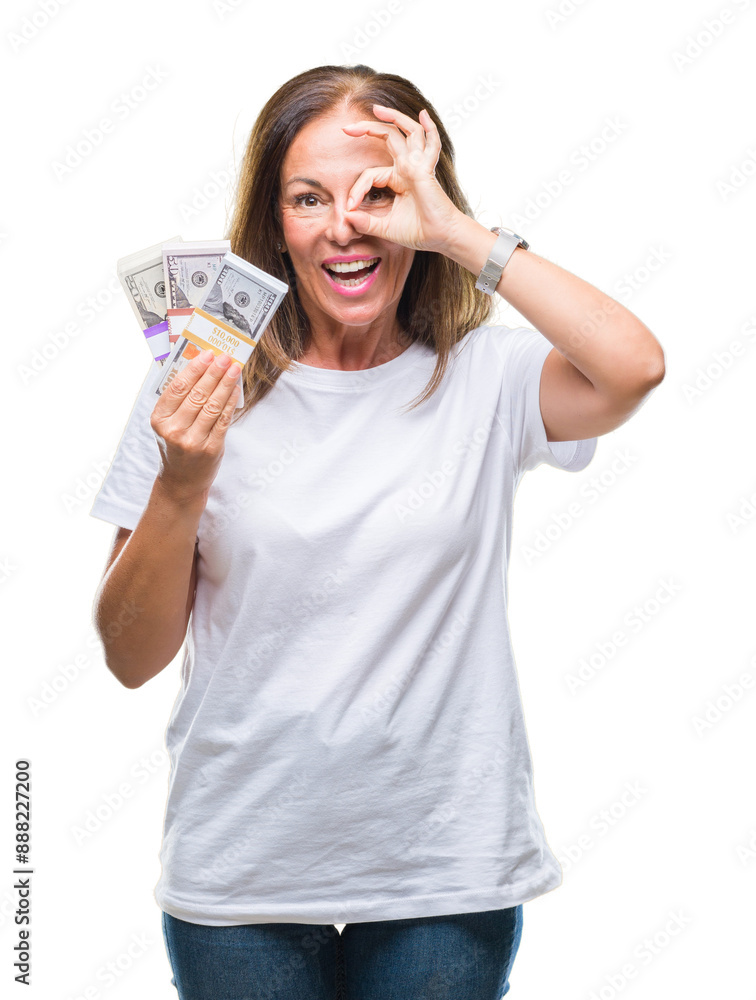 Middle age hispanic woman holding bunch of dollars over isolated background with happy face smiling doing ok sign with hand on eye looking through fingers Middle age hispanic woman holding bunch of dollars over isolated background with happy face smiling doing ok sign with hand on eye looking through fingers