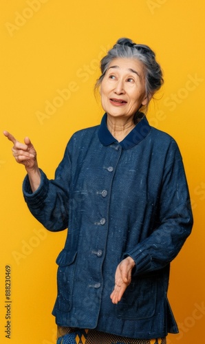 Elderly woman gesturing with her hand against a yellow background