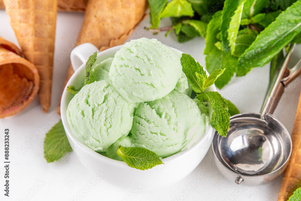 Green mint or melissa homemade ice cream, refreshing sweet sorbet dessert in serving bowl, with waffle ice cream cones on white background Green mint or melissa homemade ice cream, refreshing sweet sorbet dessert in serving bowl, with waffle ice cream cones on white background