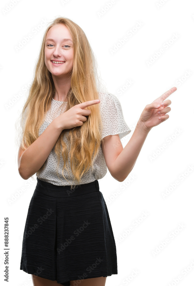 Obraz premium Blonde teenager woman wearing moles shirt smiling and looking at the camera pointing with two hands and fingers to the side.