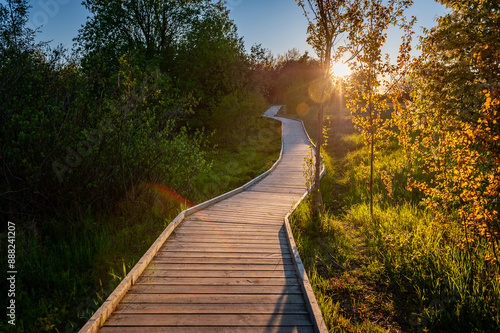 Boardwalk through flood meadows to the seashore. Sunset on the Baltic Sea. Hiking trail in Paljassaare, Tallinn,  Estonia. photo