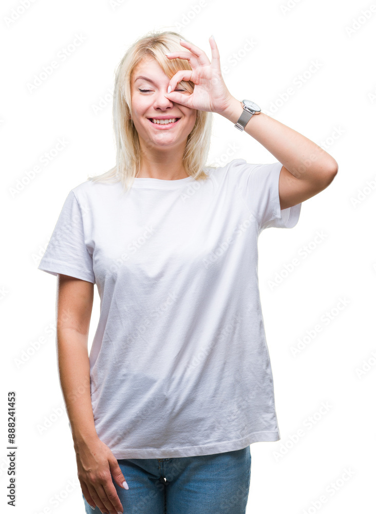Fototapeta premium Young beautiful blonde woman wearing white t-shirt over isolated background doing ok gesture with hand smiling, eye looking through fingers with happy face.