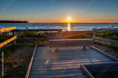 Boardwalk through flood meadows to the seashore. Observation deck with bench at sunset. Hiking trail in Paljassaare, Tallinn,  Estonia. photo