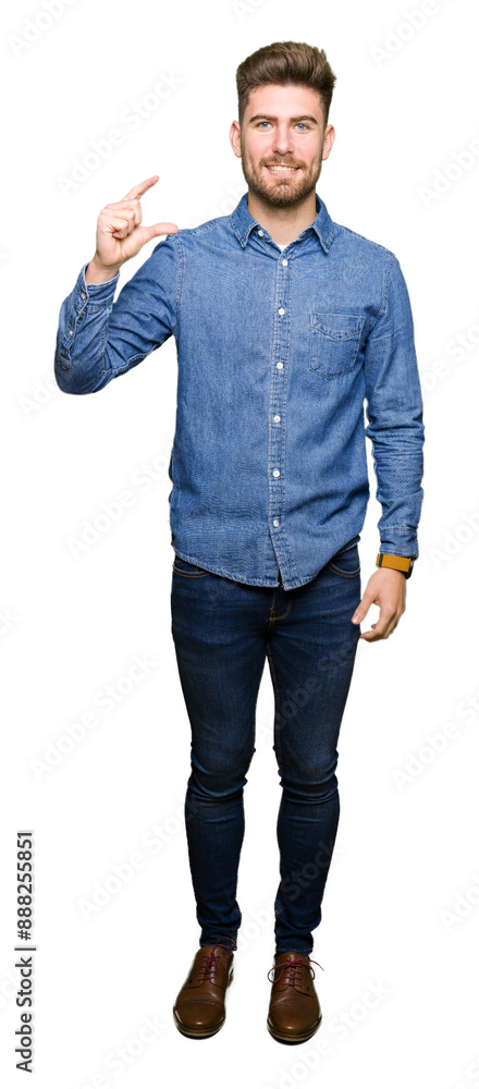 Young handsome blond man wearing casual denim shirt smiling and confident gesturing with hand doing size sign with fingers while looking and the camera. Measure concept. Young handsome blond man wearing casual denim shirt smiling and confident gesturing with hand doing size sign with fingers while looking and the camera. Measure concept.