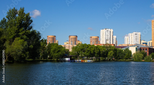 Beautiful panoramic landscape - modern high-rise buildings on the shore of a pond among the lush foliage of trees in Reutov, Moscow region on a clear summer sunny day photo