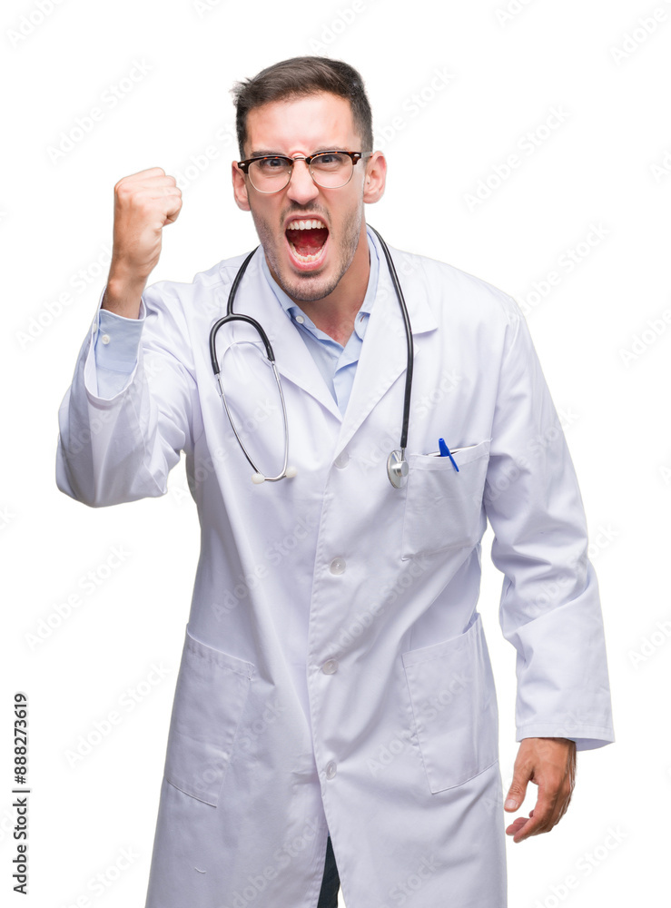 Handsome young doctor man angry and mad raising fist frustrated and furious while shouting with anger. Rage and aggressive concept. Handsome young doctor man angry and mad raising fist frustrated and furious while shouting with anger. Rage and aggressive concept.