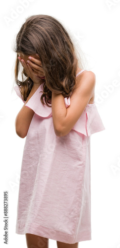 Brunette hispanic girl wearing pink dress with sad expression covering face with hands while crying. Depression concept.