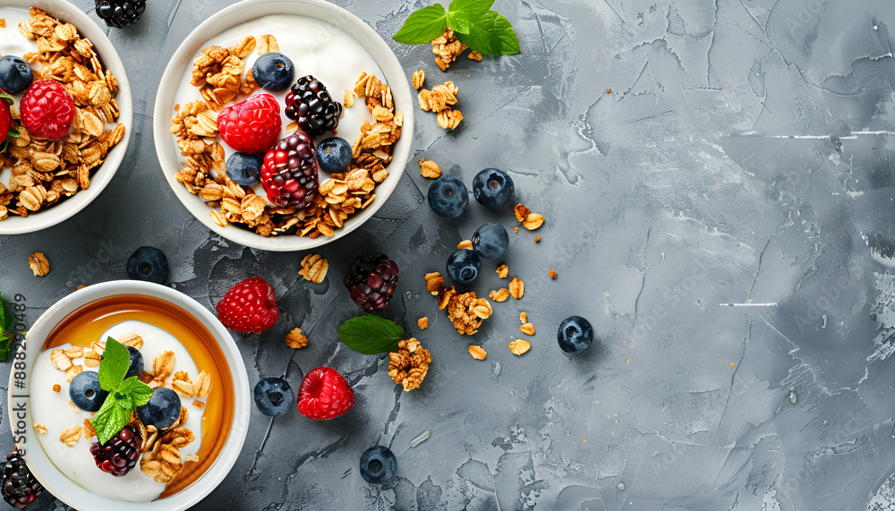 Tasty granola with berries, yogurt and honey on grey textured table, flat lay Tasty granola with berries, yogurt and honey on grey textured table, flat lay