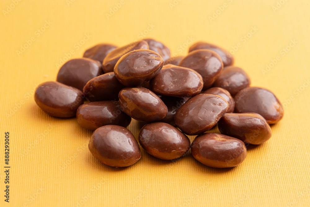 Sweet Chocolate Covered Caramel Disks on Yellow Background Sweet Chocolate Covered Caramel Disks on Yellow Background