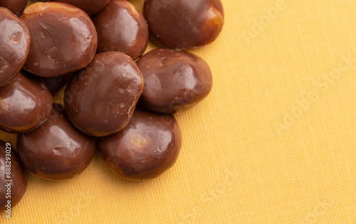 Photography Sweet Chocolate Covered Caramel Disks on Yellow Background