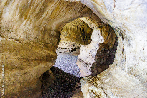 Underground tunnels inside cave in a rock formation at Logne Castle, irregular and grooved rock walls, illuminated with light lamps, summer day in Ferrieres, Belgium photo