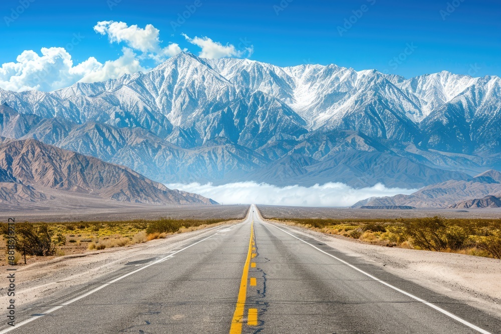 Fototapeta premium Asphalt Road Leading to Snowy Mountain Range