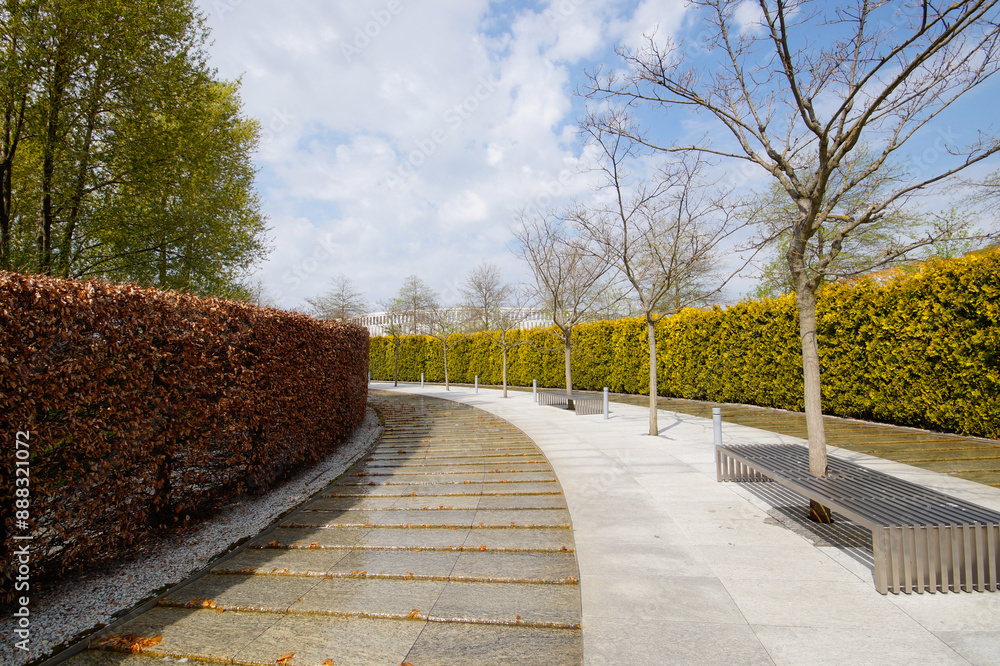 City park Krasnodar. An artificial fast-flowing river with granite banks flows around an evergreen hedge with a seating area. Public landscape Galitsky Park for recreation and walks